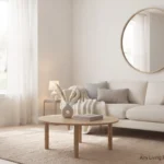 Bright and airy living room with a neutral cream sofa, round oak coffee table, sheer linen curtains, and a round wall mirror.